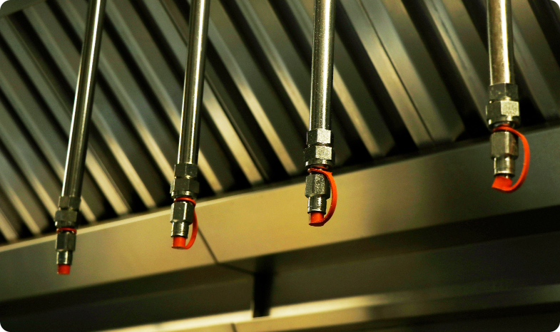 Kitchen fire suppression nozzle heads hang form a kitchen ceiling in a restaurant